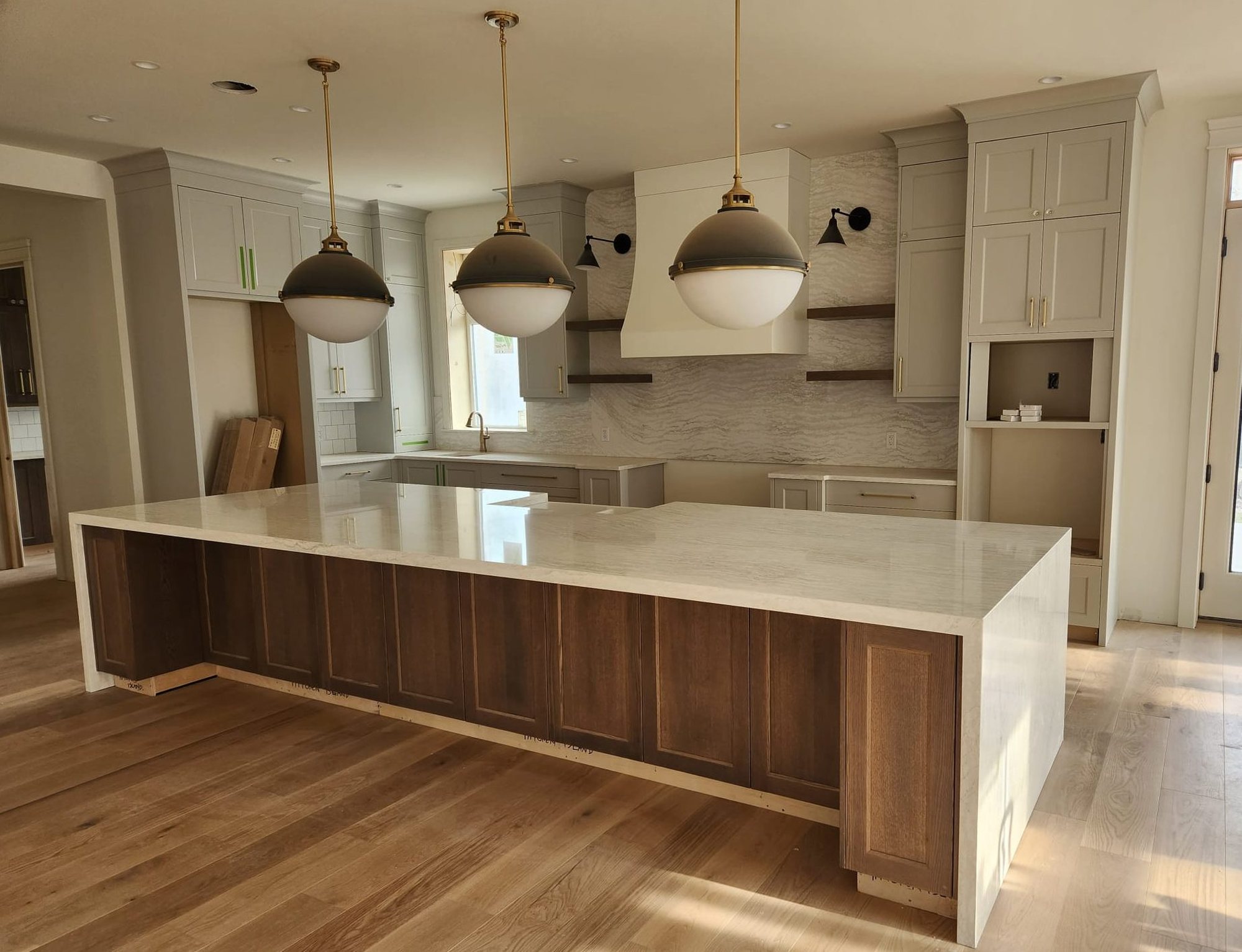 Bright open-plan Edmonton kitchen with a large white quartz waterfall island and walnut cabinetry by JC Countertops